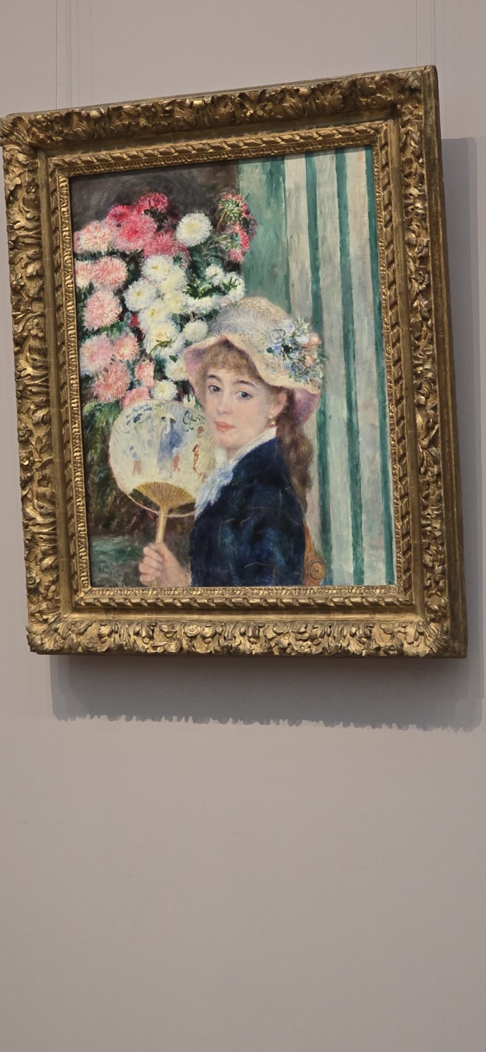 A hanging impressionist painting of "Woman with a Fan" by Pierre-Auguste Renoir